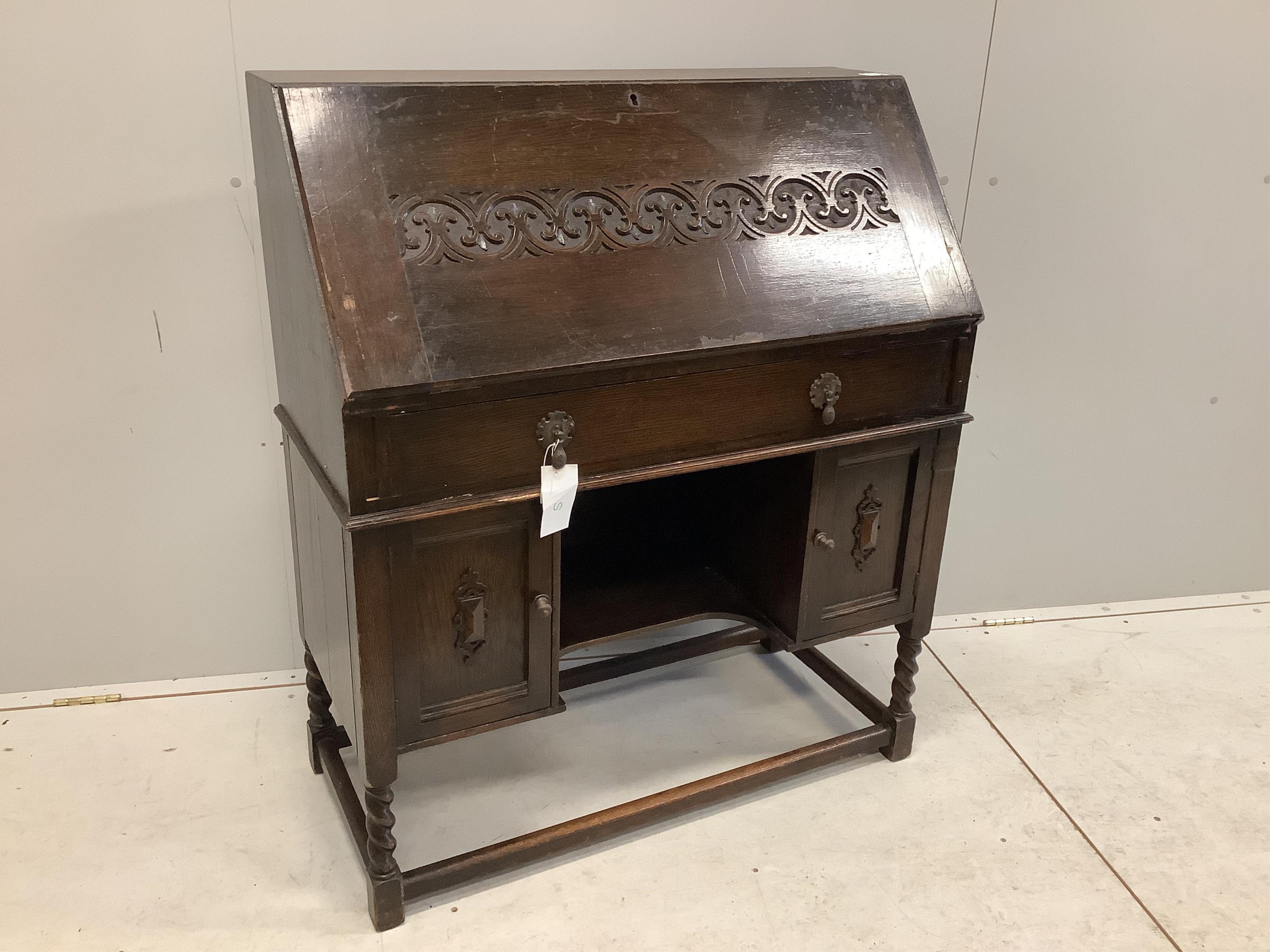 A dark oak Tudor style bureau with a decorative carved front, single drawer above cupboard doors, width 91cm, depth 42cm, height 109cm. Condition - fair